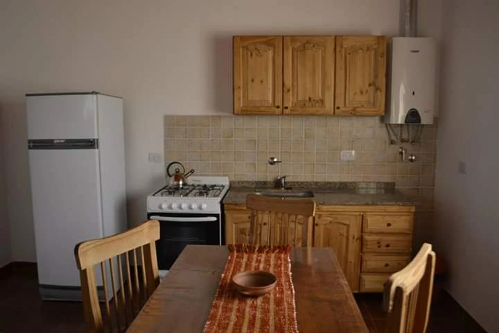 Mesa de comedor frente al horno, la heladera y los muebles de cocina.
